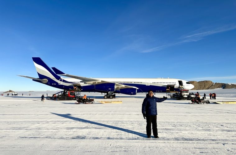 a man standing in the snow next to an airplane