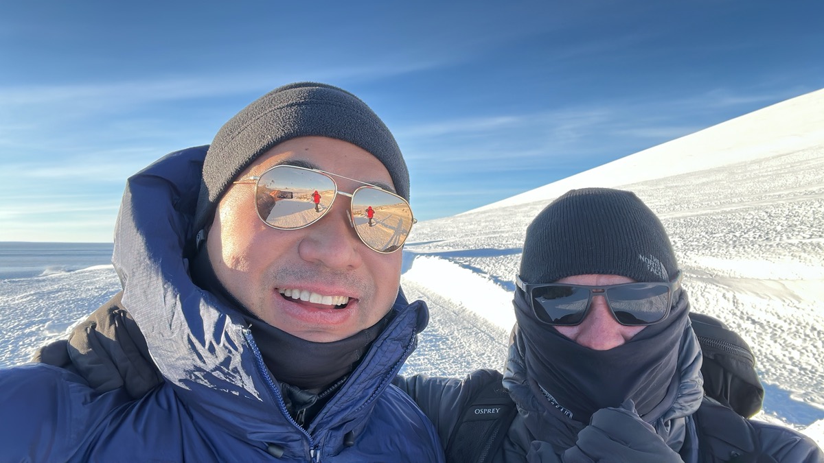 a selfie of two men in sunglasses and hats in snow