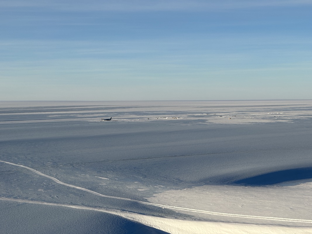 a large flat snowy area with a plane in the distance