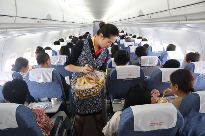 a woman serving food in a basket on an airplane
