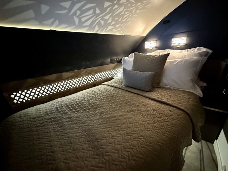a bed with pillows and a light on the wall