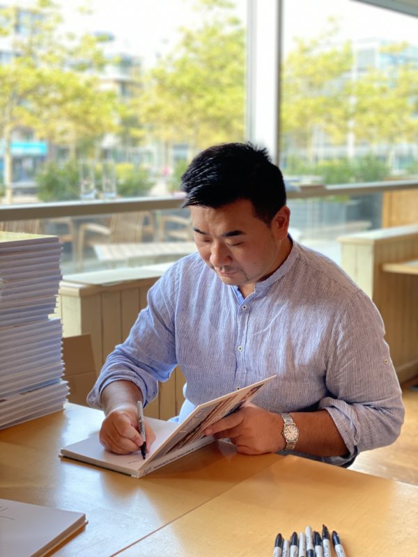 a man sitting at a table writing on a book
