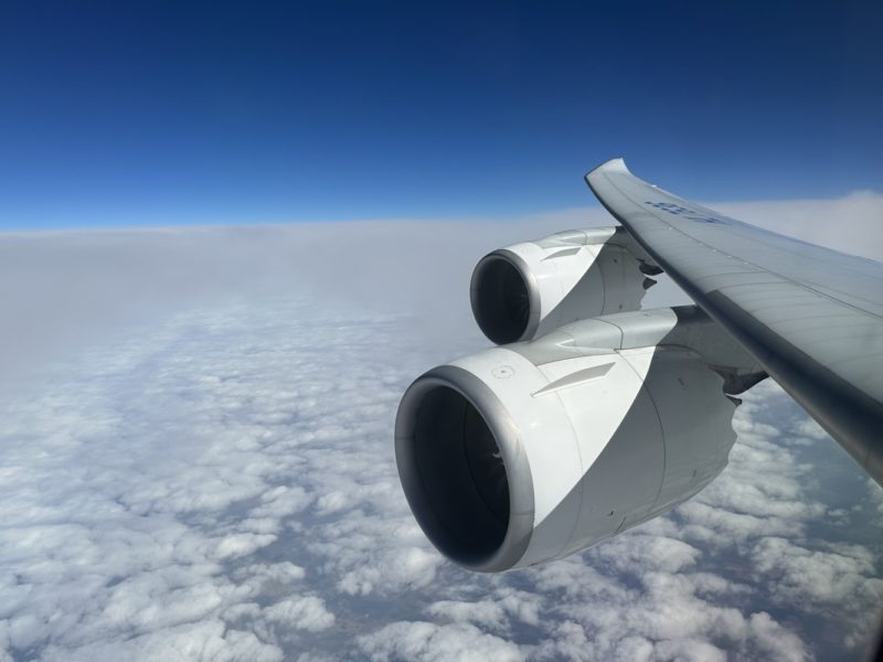 a plane wing with two engines above clouds